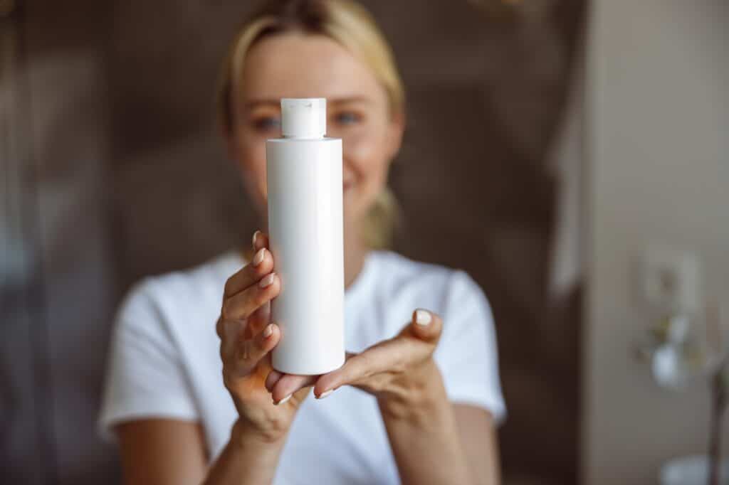 Close up of face lotion or moisturizer in hands of attractive young blonde woman. Beauty