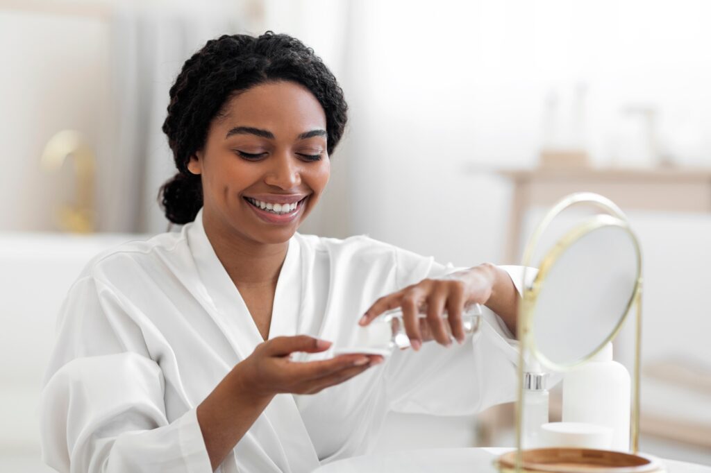 Smiling Black Female Using Cotton Pad And Micellar Water For Skincare Routine