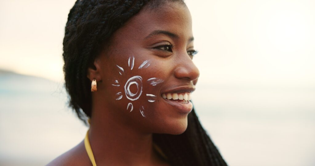 Beach, face and black woman with sunscreen for skincare, uv protection or beauty at sunset. Ocean,