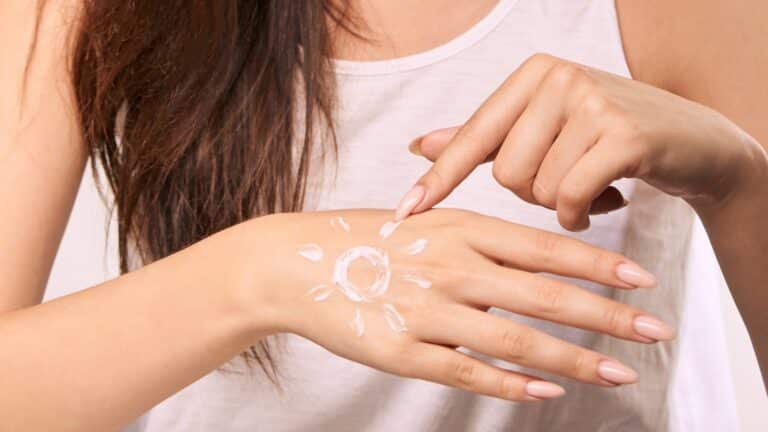 Woman applying sunscreen with sun design on hand promoting skincare and sun
