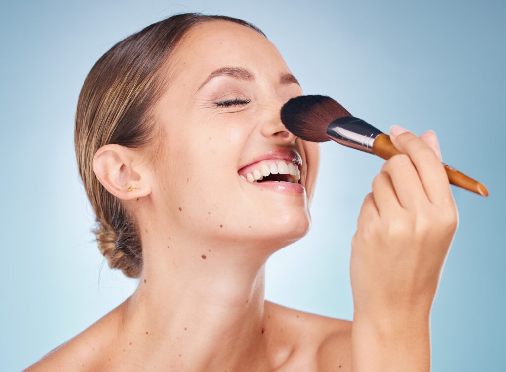 Woman, face and smile with makeup brush for skincare beauty, dermatology wellness and cosmetics tre